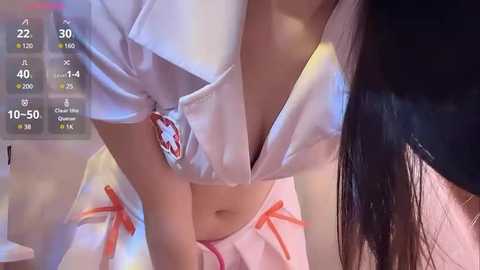 Media: A video of a woman with long black hair, wearing a revealing white nurse outfit with red bows, leaning over a man's face. The background is blurry.