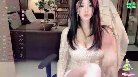 Media: A video of an Asian woman with long black hair, wearing a white lace dress, sitting in a modern living room.