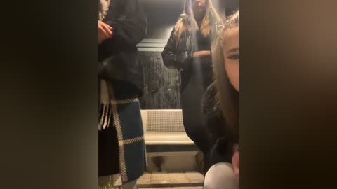 Media: Video of five women in a dimly-lit, narrow hallway, dressed in black leather jackets and high heels, carrying shopping bags, looking towards the camera.