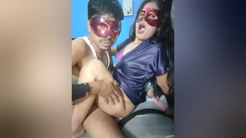 Media: Video of two Asian men in red masks, one carrying the other, both in tight, revealing clothing; blue and purple backgrounds.