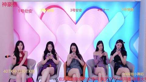 Media: A video of five young Asian women, dressed in casual clothes, seated in modern chairs, watching a smartphone screen, with a pastel heart backdrop and Chinese text.