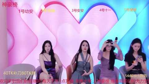 Media: Video of three Asian women in dresses, seated in front of a pink and blue heart-shaped backdrop, holding smartphones, during a live-streaming event.