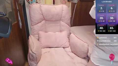 Media: Video of a pink, plush, overstuffed recliner chair with a cushioned headrest and matching throw pillows in a cozy, dimly lit room. A digital display on the right shows temperature settings and controls.