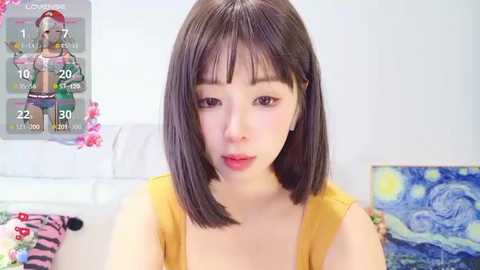 Media: Video of an Asian woman with straight, shoulder-length dark hair, wearing a mustard-yellow tank top, in a brightly lit room with a Van Gogh painting on the wall.