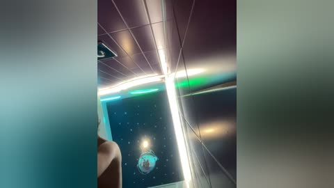 Media: Video of a futuristic room with dark walls and ceiling, illuminated by a bright, neon-blue light strip. A person with a white headband stands in the foreground, partially obscured. The room's design evokes a space-themed atmosphere.