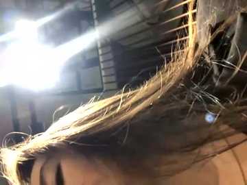 Media: A close-up video of a woman's tousled, light brown hair, partially illuminated by sunlight, with an industrial background featuring metal beams and shadows.