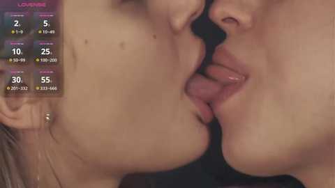 Media: A video of two women passionately kissing, with their lips pressed against each other's. Their faces are close, and their skin is smooth and tan. The background is blurred, focusing on their intimate moment.