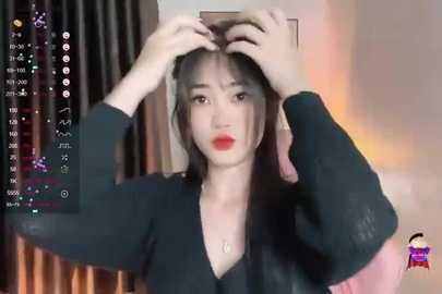 Media: Video of an Asian woman with long black hair, wearing a black sweater, adjusting her hair in a dimly lit room.