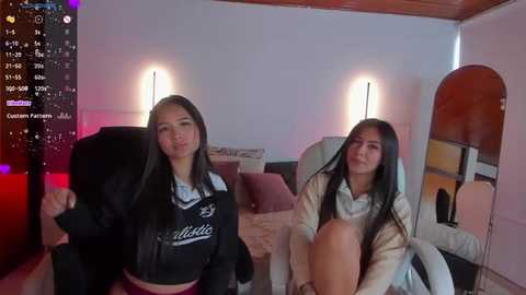 Media: Video of two young Asian girls in school uniforms, one sitting on a couch, the other standing, in a cozy, dimly-lit room with modern decor.