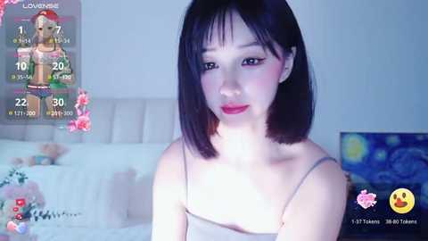 Media: A video of an Asian woman with straight black hair, wearing a spaghetti strap top, standing in a dimly lit room with a bed, a digital clock, and a colorful digital overlay.