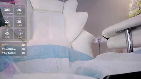 Media: A video shows a white, plush, reclining massage chair with a light blue cover. Digital temperature and vibration controls are displayed on the left side. The background is minimalistic with a hint of a plant.