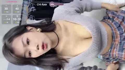 Media: Video of an East Asian woman with medium-length dark hair, wearing a gray knit top and plaid skirt, lying on a bed, with a \"Cript Rate\" overlay displaying numbers.