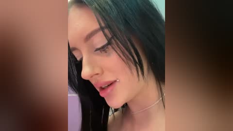 Media: A close-up video of a young woman with straight, dark hair, fair skin, and a silver nose ring. She has a soft, relaxed smile, and the background is blurred and indistinct.