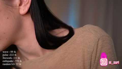 Media: Video of a woman with fair skin and long, straight black hair, wearing a tan sweater. Background is blurred, focusing on her hair and shoulder. Text reads \"Wicked Pixie's fine hair extensions in Caramel 33/30.\