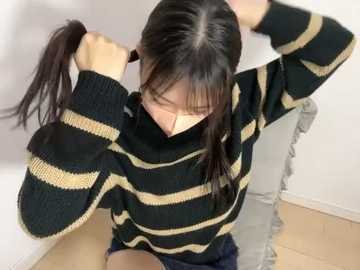 Media: Video of an Asian woman with long black hair, wearing a black and beige striped sweater, sitting on a wooden floor, playing with her hair.