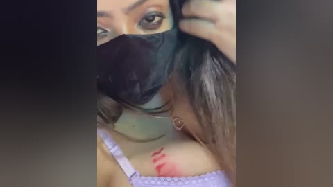 Media: Video of a woman with long, dark hair, wearing a black face mask and a light purple lace bra, with red lipstick marks on her collarbone.