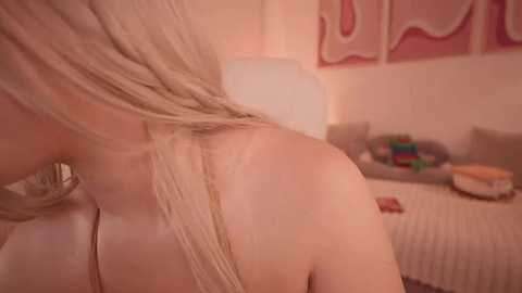 Media: Video of a young woman with light skin and blonde hair, partially topless, leaning against a wall. The background features a pink and white bedroom with a bed, stuffed animals, and a colorful blanket.