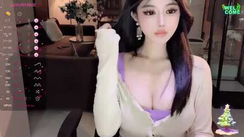 Media: A video of an East Asian woman with fair skin and long black hair, wearing a low-cut purple top, sitting indoors.