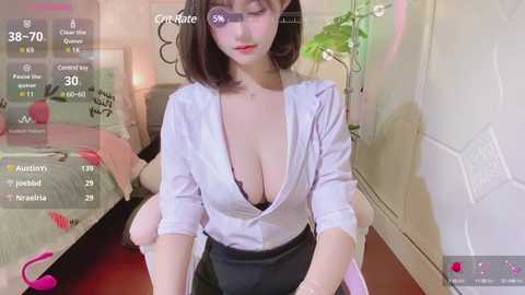 Media: Video of a young Asian woman with short black hair, fair skin, wearing a low-cut white blouse revealing a black bra, sitting on a bed in a dimly lit bedroom.