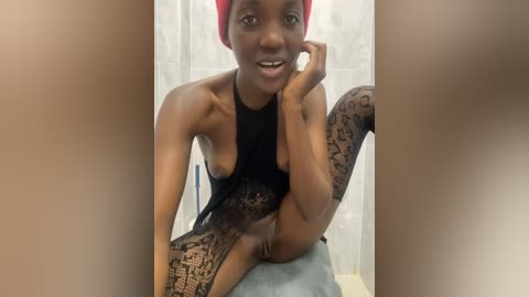 Media: A video of a slim, dark-skinned woman with a red headscarf, wearing black lace stockings and a black top, sitting on a bathtub, smiling seductively.