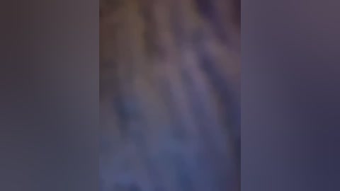 Media: Blurry video of a person in a dark room with indistinct features, possibly wearing a light-colored shirt, and standing in front of a partially visible wall with muted, dark colors.