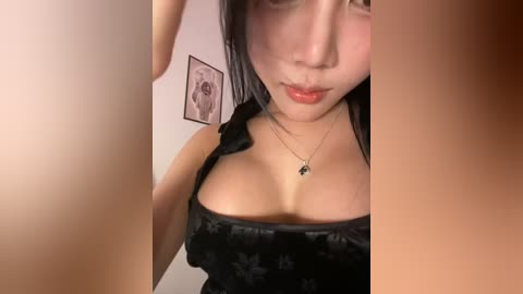 Media: Video of an Asian woman with fair skin, dark hair, and red lips, wearing a black satin corset, standing in a dimly lit room with a framed picture on the wall.