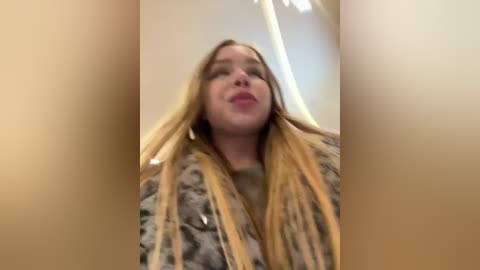 Media: A blurry video of a young woman with long, straight blonde hair, wearing a patterned shirt, taken from a low angle, giving a distorted, distorted perspective.