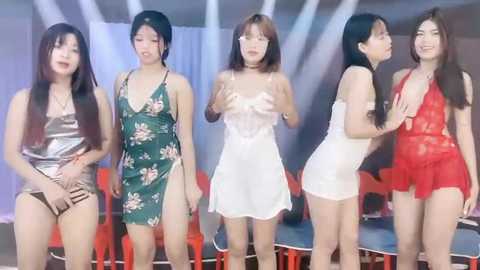 Media: Video of five Asian women in various lingerie, posing in a studio with white curtains and red chairs.