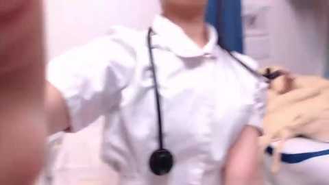 Media: Video of a white, male doctor in a white lab coat, examining a child's chest with a stethoscope. The child's face is blurred. Background includes medical equipment and a blue curtain.