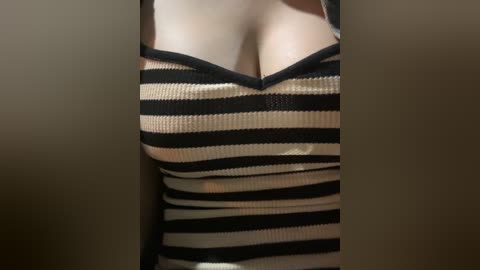 Media: Video of a woman's cleavage, showing black and beige horizontal stripes on a tight, ribbed fabric, revealing ample cleavage and a hint of areola.