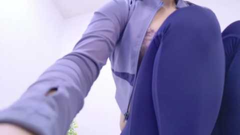 Media: Video of a man in a grey blazer, unzipped to reveal a purple shirt, taking a selfie from a low angle.