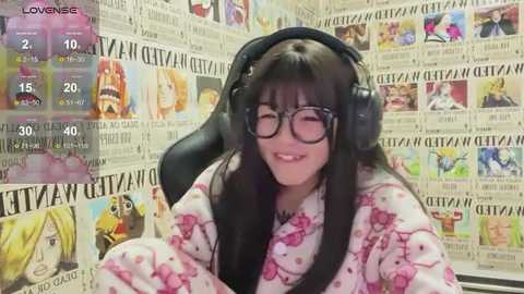 Media: A video of a young Asian woman with long black hair, wearing black-rimmed glasses, a floral kimono, and large headphones, seated in a chair surrounded by newspaper clippings.