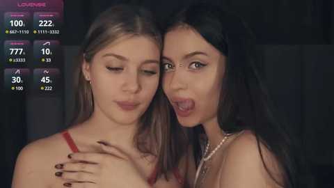 Media: Video of two young women with light skin, one with straight brown hair, the other with wavy black hair, both wearing red tops, close together, smiling, dimly lit background.