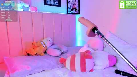 Media: A video of a plush bunny with a pink and white striped hat lying on a bed with a pink and blue neon light, surrounded by other plush toys.