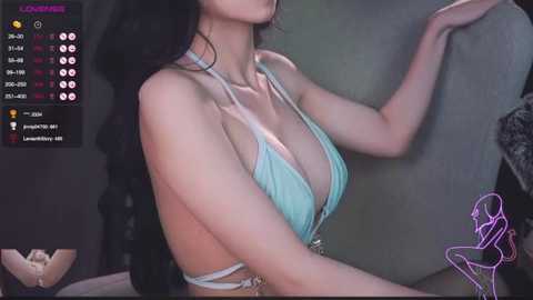 Media: Video of a slender, fair-skinned woman with long, black hair in a low-cut, mint green bikini, posing against a dark backdrop. Streaming platform interface with user statistics and chat icons in the top left corner.