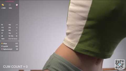 Media: Video of a woman's midsection in a green and white cropped top, revealing a flat stomach and hint of underwear. Background shows a smartphone screen with fitness app metrics.