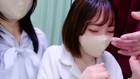 Media: Video of two women in white masks, one with straight black hair, the other with straight brown hair, both in white lab coats, in a sterile medical setting.