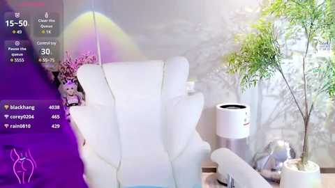 Media: Video of a modern living room with a white armchair, a green plant, and a white lamp on a wooden table. A young child sits in the armchair, smiling, surrounded by virtual avatars and social media icons.