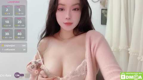 Media: A video of a young Asian woman with long black hair, fair skin, wearing a light pink lace bra, standing in a bedroom with a digital clock and curtains.