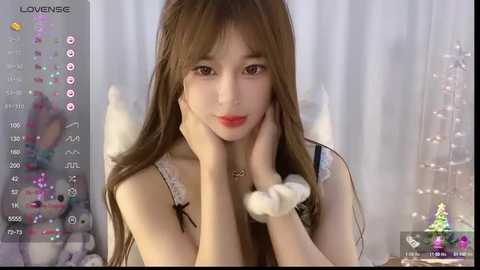 Media: Video of a slender East Asian woman with long brown hair, wearing a white lace top and fluffy wrist scrunchie, smiling softly, with a white background.