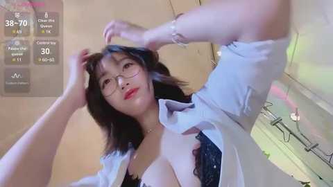 Media: Video of an Asian woman with shoulder-length black hair, wearing glasses, an open white shirt, and a black lace bra, posing seductively in a bathroom.