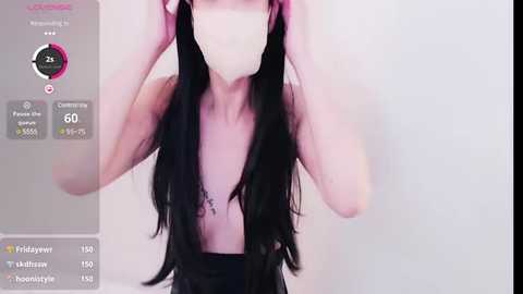 Media: A video of a pale-skinned, slender person with long, black hair wearing a face mask, holding the hair, against a plain, light background.