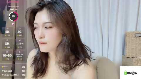 Media: Video of an East Asian woman with shoulder-length dark hair, light skin, and a slender build, wearing minimal makeup, captured in a modern, well-lit room with beige curtains.