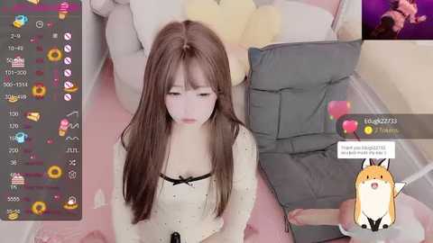 Media: Video of a young Asian woman with long brown hair, wearing a white blouse, kneeling in a pastel-themed room. Screenshots of an online chat show comments and emojis.