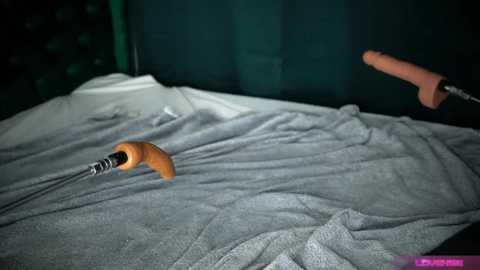 Media: Video of a dimly lit room with a grey blanket covering a bed, featuring a wooden-handled screwdriver on the left and a flesh-colored dildo on the right, both partially obscured.