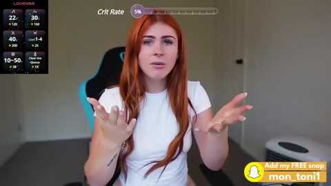 Media: Video of a young woman with long red hair, wearing a white T-shirt, seated on a black gaming chair. The background shows a minimalist room with a gray floor and a toilet.