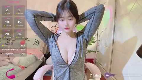 Media: Video of a young East Asian woman with long black hair, wearing a low-cut grey top, posing seductively in a bedroom with a pink vibrator and a digital clock.