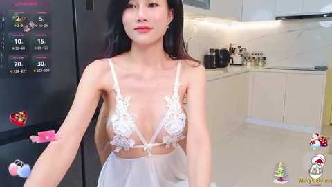 Media: A video of an Asian woman with long black hair, fair skin, and small breasts, wearing a sheer white lace lingerie set, standing in a modern kitchen.