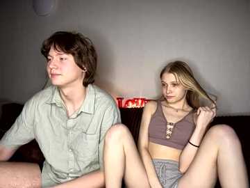 Media: Video of two young people, a boy and a girl, sitting close together on a couch, looking at each other, in a dimly lit room.