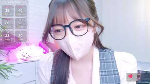 Media: Video of an East Asian woman with straight, light brown hair and glasses, wearing a white mask and plaid vest over a white top, indoors with a purple light and calendar background.